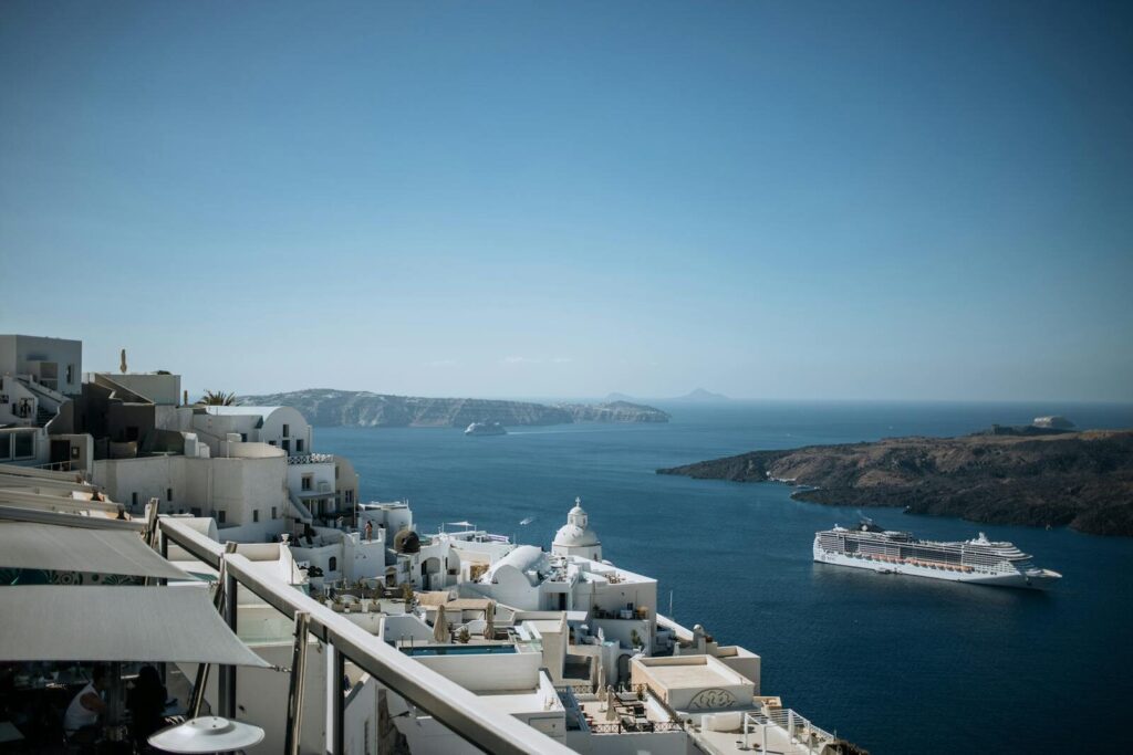 Breathtaking view of Santorini's whitewashed buildings with a cruise ship in the Aegean Sea.