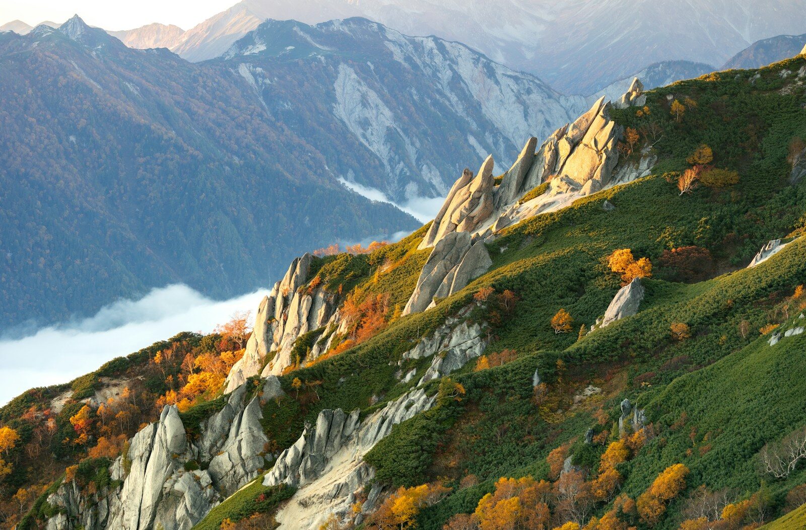 Jagged mountain ridge with autumn foliage and clouds