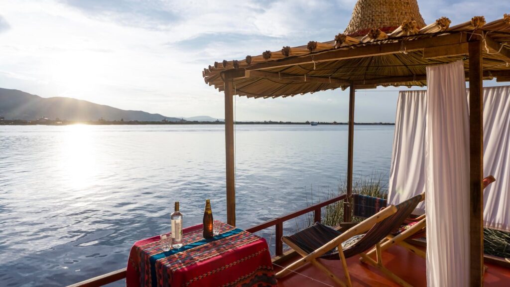 Relaxing view of Lake Titicaca at a lodge with deck chairs and drinks.