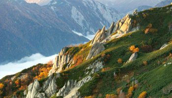 Jagged mountain ridge with autumn foliage and clouds